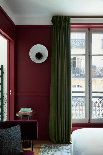 a bedroom with red walls and a window with green curtains at Hôtel Le Ballu in Paris