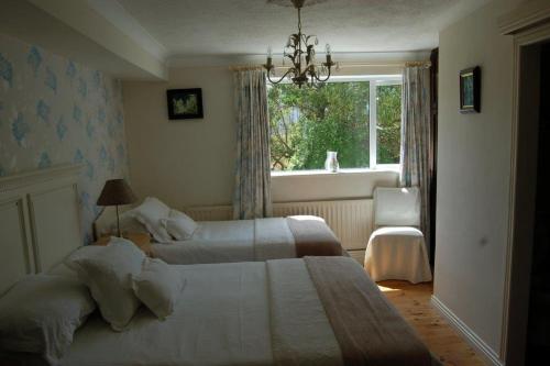 a bedroom with two beds and a window and a chair at Teach An Easard in Clifden