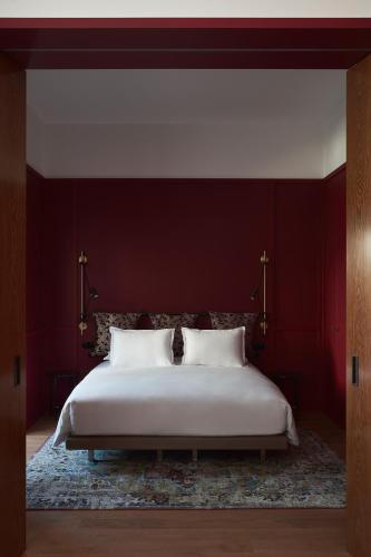a bedroom with a large white bed with red walls at Hôtel Le Ballu in Paris