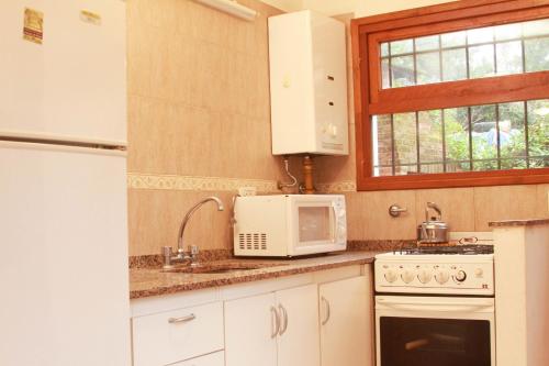 een keuken met een magnetron, een fornuis en een raam bij Acuarela in Villa Gesell