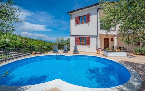 a villa with a swimming pool in front of a house at Serene Summer Oasis - Pool, Jacuzzi, Sauna, Sea View - Lara in Drenje