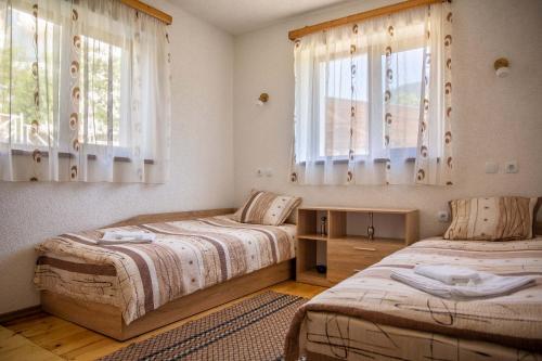 two beds in a room with two windows at Villa Samodiva in Yagodina