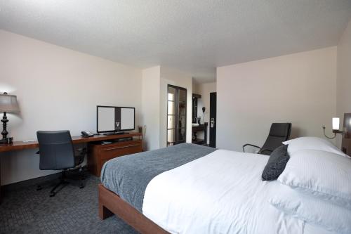 a bedroom with a bed and a desk and two chairs at Hotel V in Gatineau