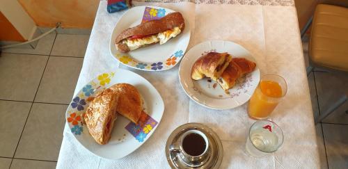three plates of food on a table with bread and orange juice at Alexia's Apartments in Rio