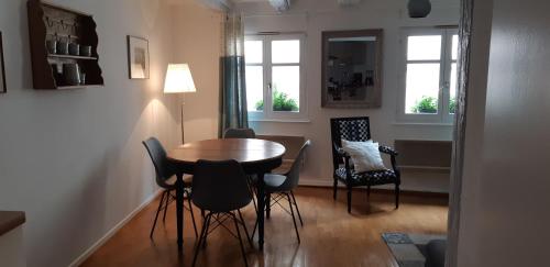 une salle à manger avec une table et des chaises et deux fenêtres dans l'établissement Margot - hyper centre Colmar, à Colmar