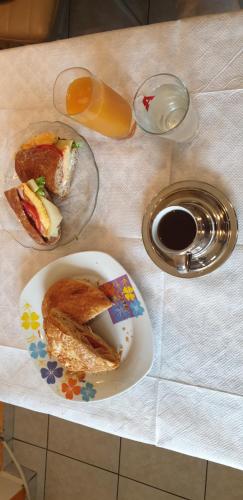 a table with a plate of sandwiches and a glass of orange juice at Alexia's Apartments in Rio