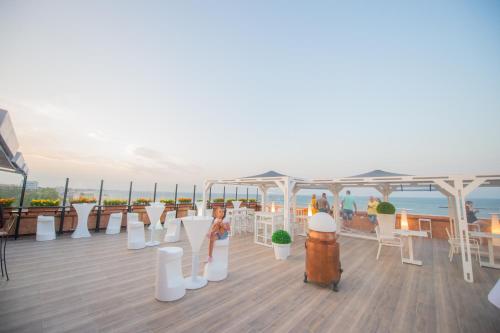 a deck with white chairs and tables on a roof at Hotel Ges in Mamaia