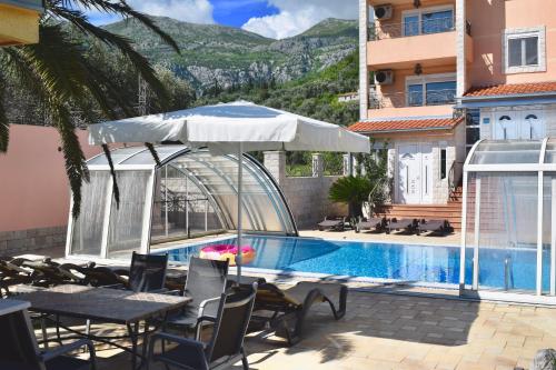 a hotel with a swimming pool with chairs and an umbrella at Villa Dolphin Apartments in Petrovac na Moru