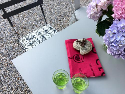 una mesa con dos vasos y un libro y flores en Au Sigala, en Lisle-sur-Tarn