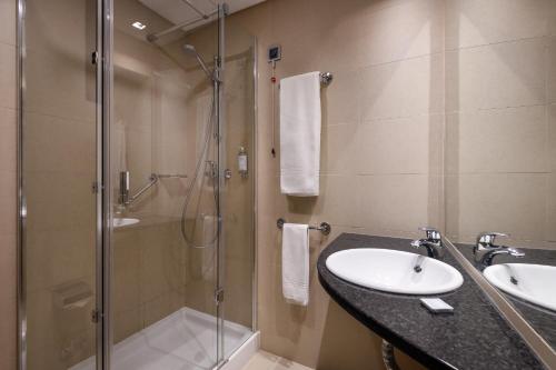 a bathroom with a glass shower and a sink at Hotel Aveiro Palace in Aveiro