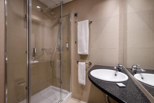 y baño con ducha acristalada y lavamanos. en Hotel Aveiro Palace, en Aveiro