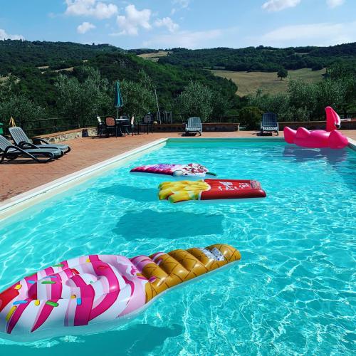 a swimming pool with several inflatables in the water at Podere le Mulina in Castiglione dʼOrcia