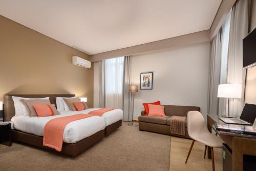 Habitación de hotel con cama y sofá en Hotel Aveiro Palace, en Aveiro