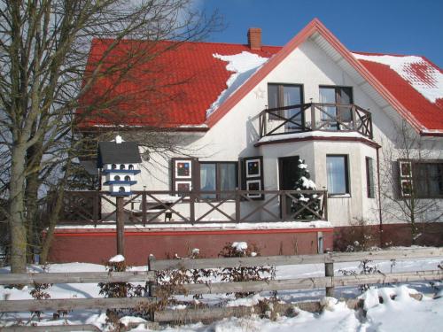 una casa blanca con techo rojo en la nieve en Łosiowy Kąt, en Goniądz