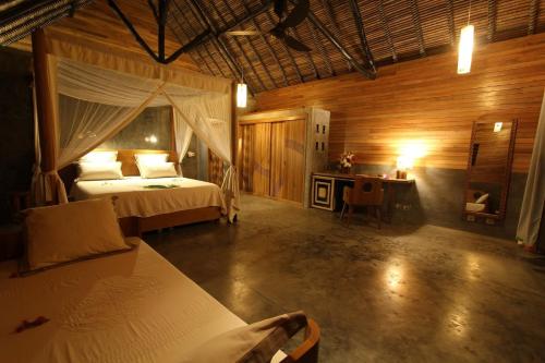 a bedroom with a bed and a desk in a room at L'heure Bleue in Ambatoloaka