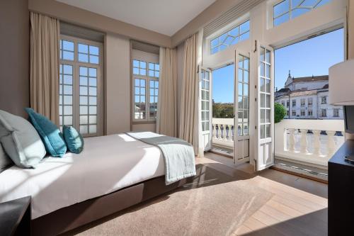 a bedroom with a large bed and large windows at Hotel Aveiro Palace in Aveiro