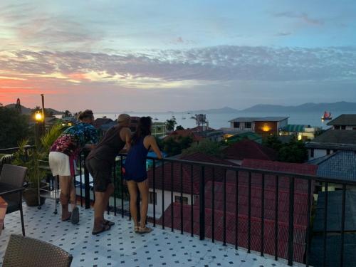 a group of people standing on a balcony looking at the sunset at The Villager Fishermans Village in Bophut