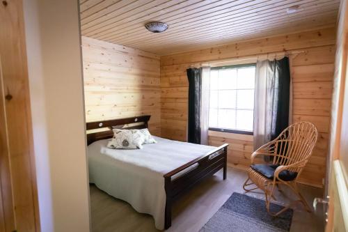 a bedroom with a bed and a window and a chair at Villa Vahtivuori in Rantasalmi