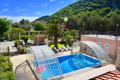 una piscina con una jaula de iguana junto a una casa en Villa Dolphin Apartments en Petrovac na Moru