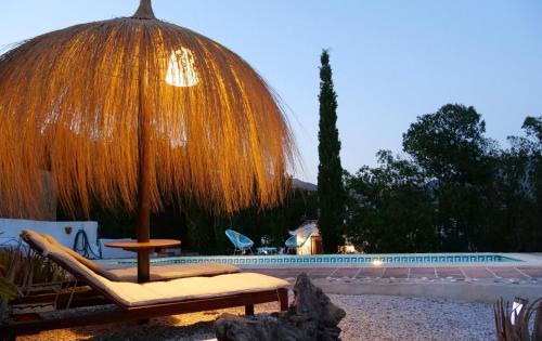einen Stuhl und einen Regenschirm neben einem Pool in der Unterkunft La Perla Andaluza in Alcaucín