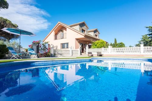 a house with a swimming pool and an umbrella at HomeHolidaysRentals Corts in Tordera