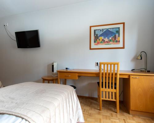 a bedroom with a desk with a bed and a television at Hotel Jahtihovi in Kuopio