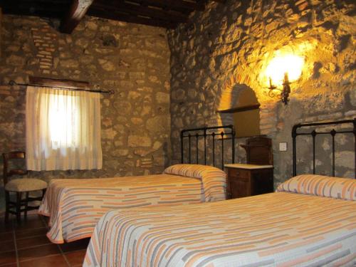a bedroom with two beds and a stone wall at Casa Rural Las Martas in Acebo