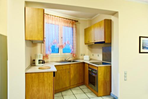 a kitchen with wooden cabinets and a sink and a window at Sea Breeze Apartments Chios in Monolia