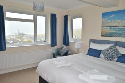 sypialnia z łóżkiem z niebieskimi zasłonami i oknem w obiekcie Fairlee, Perranporth w mieście Perranporth