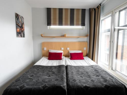 a bedroom with a bed with two red pillows at Hotel Jahtihovi in Kuopio
