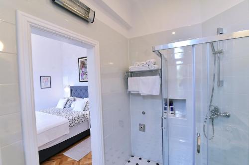 a bathroom with a walk in shower next to a bed at Villa Salus, Apartment Maruna in Opatija