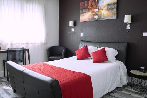 um quarto com uma cama grande e almofadas vermelhas em Cit'Hotel Europeen em Angoulême