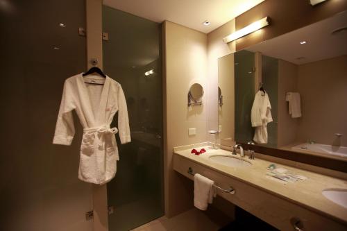 a bathroom with a sink and a robe on a mirror at Hotel y Casino Del Río - General Roca in General Roca