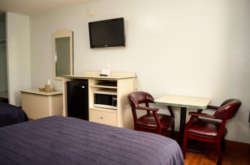 a hotel room with a bed and two chairs and a television at Economy Inn in West Palm Beach