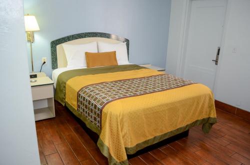 a bedroom with a large bed with a yellow blanket at Economy Inn in West Palm Beach