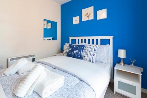 a bedroom with blue walls and a white bed with pillows at The Point Apartment, Leeds City Center in Leeds