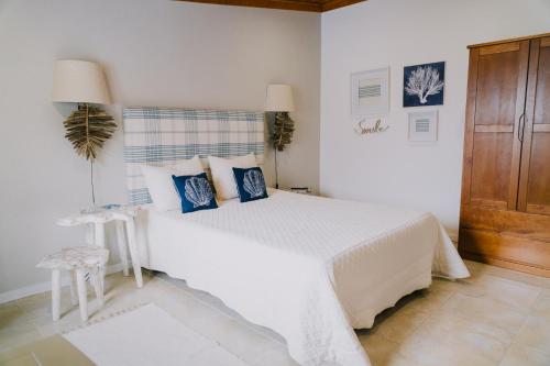 a white bedroom with a large bed with blue pillows at NorthSpot in Nazaré
