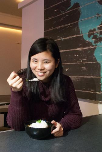 a woman sitting at a table eating a bowl of rice at Ocean Island Inn | Backpackers | Suites in Victoria
