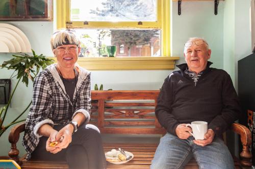 two older men sitting on a bench with a cup of coffee at Ocean Island Inn | Backpackers | Suites in Victoria