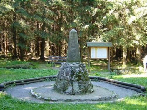 a monument in a park with a bench and trees at Gasthof Thomas Müntzer in Steinheid