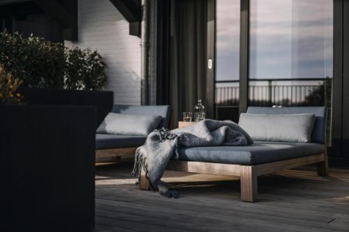 a couch sitting on a porch with a blanket on it at Strandhotel in Cadzand-Bad