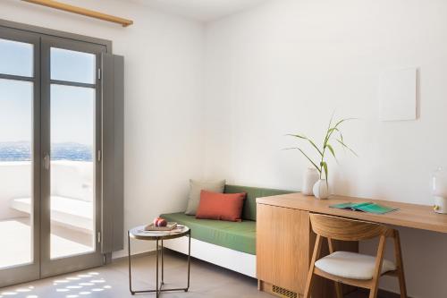 a living room with a green couch and a desk at Mykonos Soul Luxury Suites in Agios Stefanos