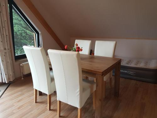 comedor con mesa de madera y sillas blancas en Havel-Pension Kruse, en Havelberg