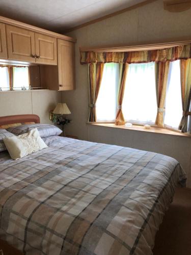 a bedroom with a bed and two windows at The Aspen in Dunoon