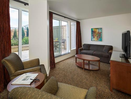 a living room with a couch and chairs and a tv at Metterra Hotel on Whyte in Edmonton