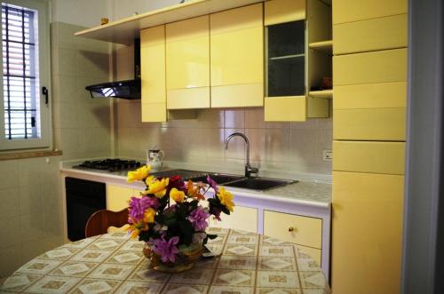 una cucina con un tavolo con un vaso di fiori sopra di Casa Lucrezia - casa vacanza Torre Canne a Torre Canne