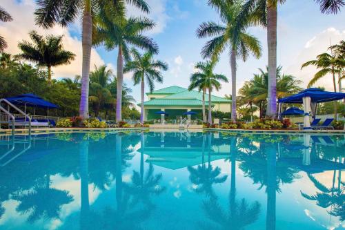 a swimming pool with palm trees and a building at Provident Doral At The Blue in Miami