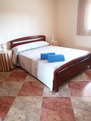 a bedroom with a bed with two blue pillows on it at EL MIRADOR DEL CORNEJA in Mesegar de Corneja