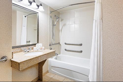 a bathroom with a white tub and a sink and a shower at Wingate by Wyndham Columbia/Lexington in Lexington