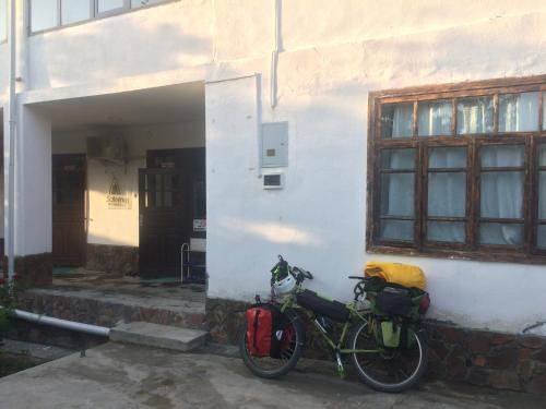 un vélo garé à côté d'un bâtiment blanc dans l'établissement Salom Hostel, à Panjakent